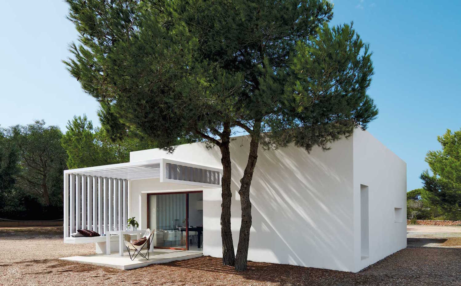 00311145. Posada sobre un suelo de grava y rodeada de pinos y sabinas, la casa se enmarca en el paisaje de Formentera.