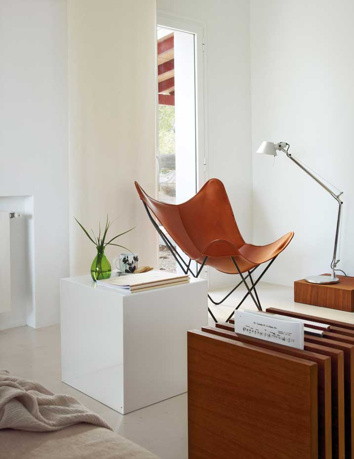 00311161. Zona de lectura equipada con la butaca Butterfly BKF y la lámpara de pie Tolomeo de Artemide sobre un pedestal de madera de iroko hecho a medida