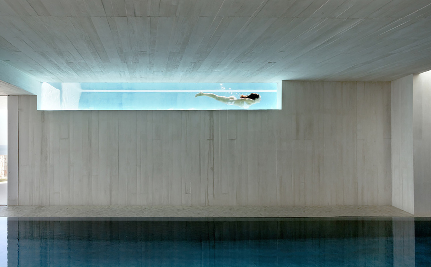 Casa Sardinera  ∏ Mariela Apollonio 2014 (20). En la planta basamento, un hueco apaisado en el muro ofrece una visión espectacular del vaso de la piscina exterior. Aquí se ha ubicado otra piscina y una zona de gimnasio