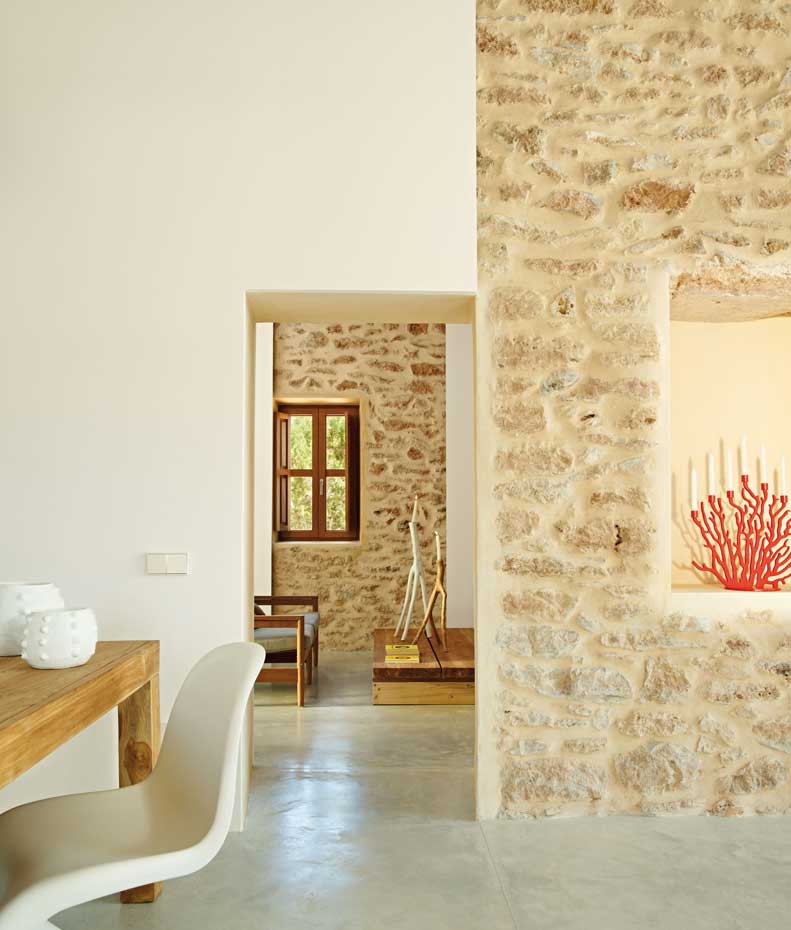 00345968. Muros de mampostería conviven con paredes encaladas y suelos de hormigón pulido en la construcción original. En primer término, silla de comedor Panton, de Verner Panton, producida por Vitra