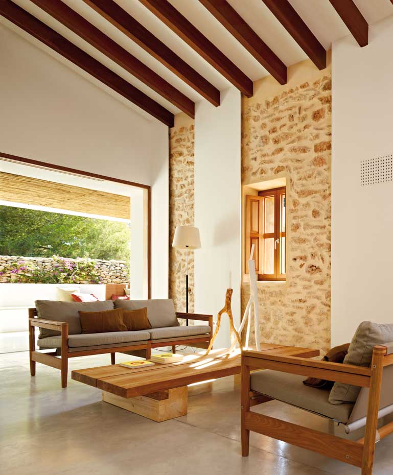 00345972. n la planta baja, los pavimentos interiores y exteriores son de hormigón pulido. Los cerramientos originales de piedra se han dejado vistos. La carpintería exterior es de madera de iroco, al igual que las vigas del forjado en la casa primitiva. Sofás, modelo Road, de Roda, diseño de Rodolfo Dordoni