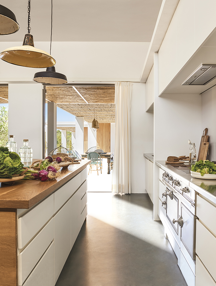 00433087. La cocina de estética retro, de La Cornue, contrasta con el mobiliario acabado laminado blanco, de líneas modernas y sobrias. Las lámparas de techo se han adquirido en la tienda Luzio de Barcelona