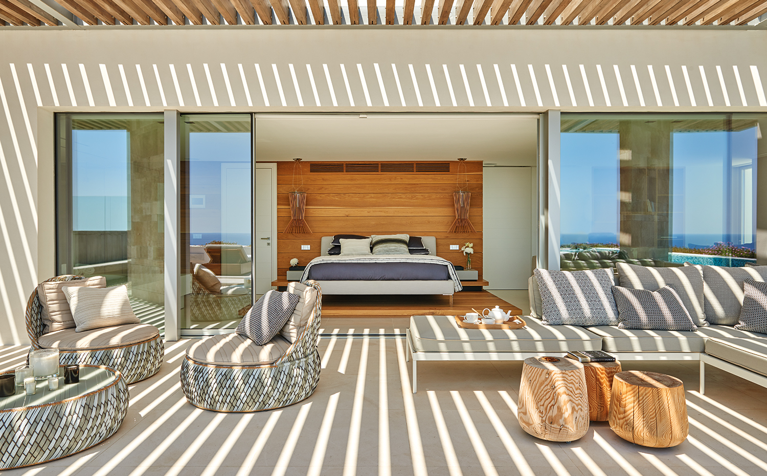 AyD-Saota(Ibiza)2237. En la terraza, sillones y mesita Dala, diseño de Stephen Burks para Dedon. Sofá Box y mesitas de madera maciza, de Okha. En el dormitorio, lámparas Allegretto, de Foscarini, y cabecero tapizado con tejido, de Romo