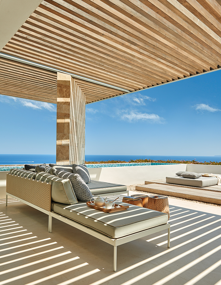 AyD-Saota(Ibiza)2240. Junto a la piscina infinity y bajo la pérgola de madera, colchonetas y cojines hechos a medida con tejidos del fabricante Kirby. Sofá Box y mesas de centro Burbuja, de Okha. Bandeja de madera, de Georg Jensen