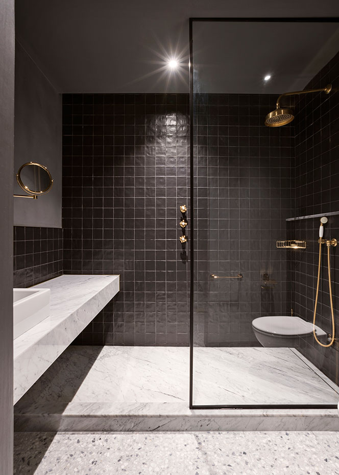 El baño sigue la idea de espacios tenues. El pavimento del baño también es de terrazo. Encimera de mármol Portobelllo y revestimiento de cerámica artesanal de color negro