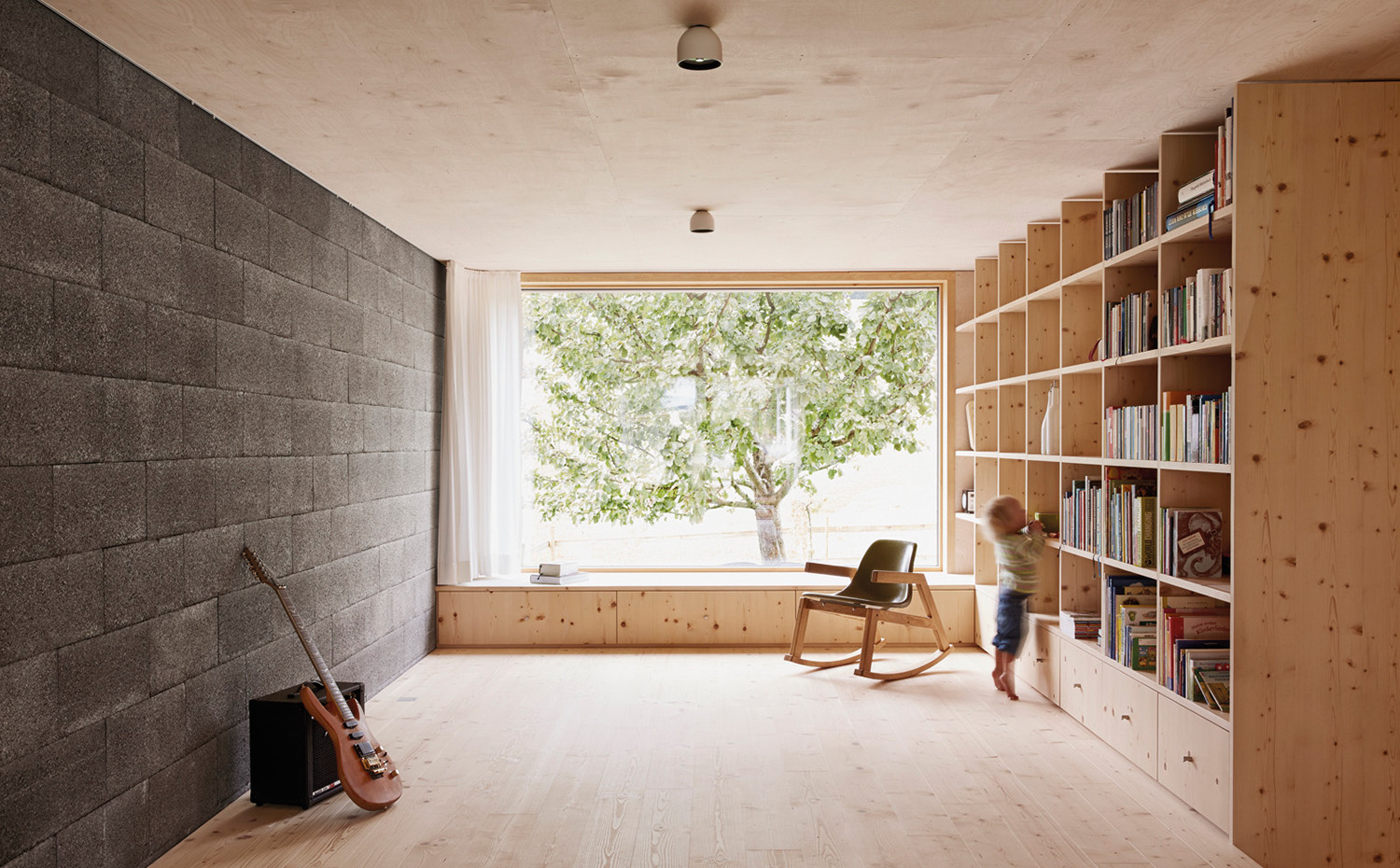 estudio Innauer-Matt crea continuidad funcional y cromática con un mueble bajo que se prolonga en la librería