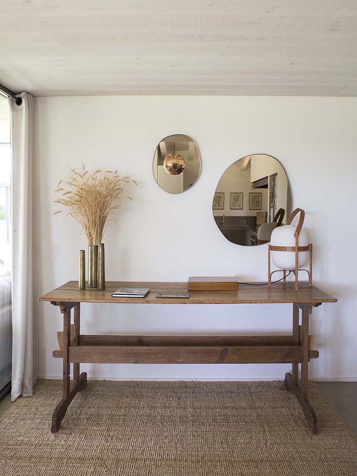 Residencia Ampurdán16 Bárbara Aurell. La mesa de madera antigua de la entrada, fue adquirida en un anticuario de la zona, y sobre ella, la lámpara Cesta, de Miguel Milá para Santa & Cole, y unos espejos de Sabine Mercelis comprados en Palau de Casavells (Gerona)