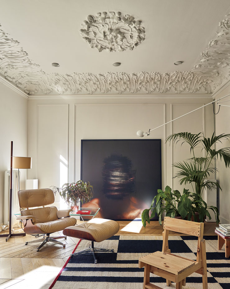 930-AyD-Aribau152 19. El salón, con obra de Manolo Menéndez como punto focal, aglutina la Lounge Chair y otomana de los Eames, editada por Vitra; alfombras de nanimarquina y la silla de Marc Morro para AOO. A la derecha, lámpara de pared de Paolo Rizatto para Flos
