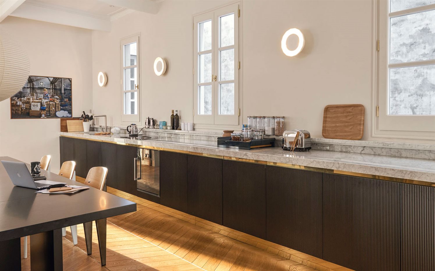 930-ok-AyD-Aribau152 23. La cocina se abre al comedor en un solo ambiente con mobiliario diseñado por Circular Studio y producido por SCP. Grifos Car 23, de Cea; placa de inducción Basic, de Bora, y apliques Scotch Club, de Xavier Mañosa & Marshallah para Marset. Fotografía del fondo de Jordi Bernadó