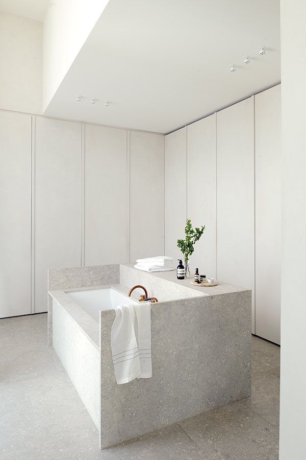 059 DSC4167. Hans Verstuyft ha diseñado los elementos del baño utilizando la misma piedra italiana del suelo. Las griferías monomando del lavamanos y de la bañera son de la firma Vola, fabricadas con latón natural. Cosmética, de Aesop.