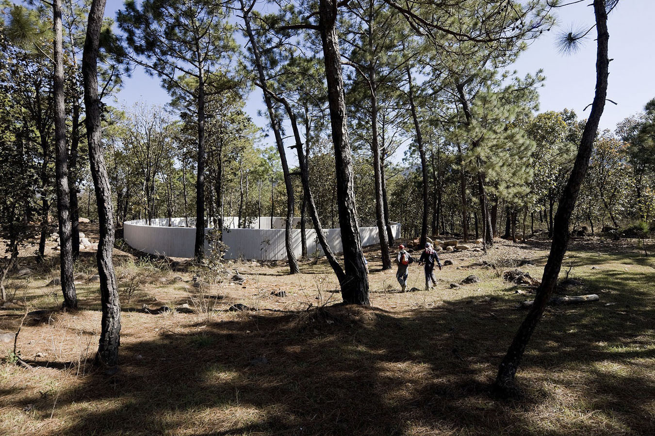 Dos peregrinos se aproximan al Santuario Circulo proyectado por Dellekamp Arquitectos