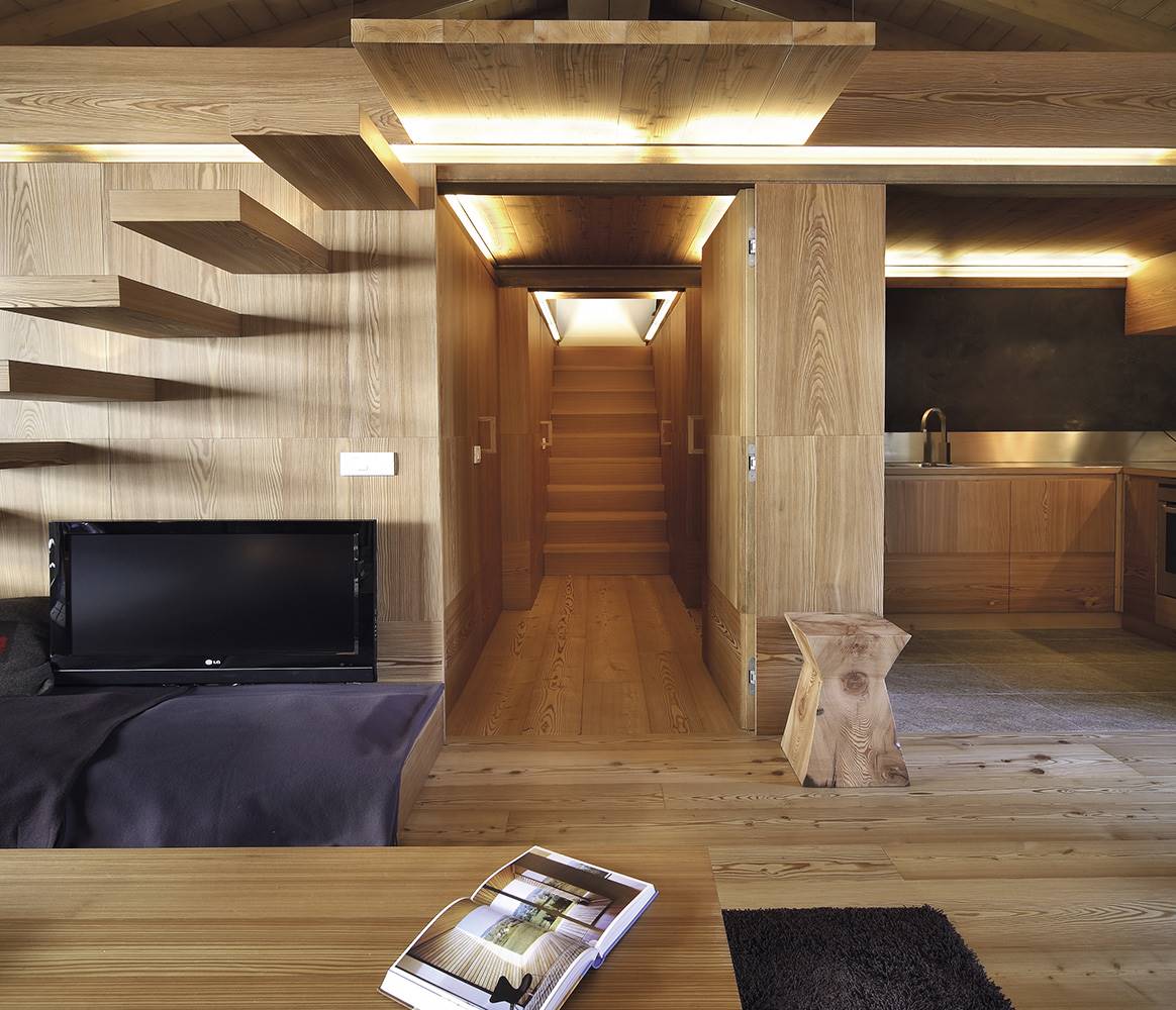 En este espacio diseñado por Studio Fanetti, la iluminación prescinde de lámparas a la vista ya que se ha preferido que queden ocultas en la propia arquitectura, retroiluminando la madera.
