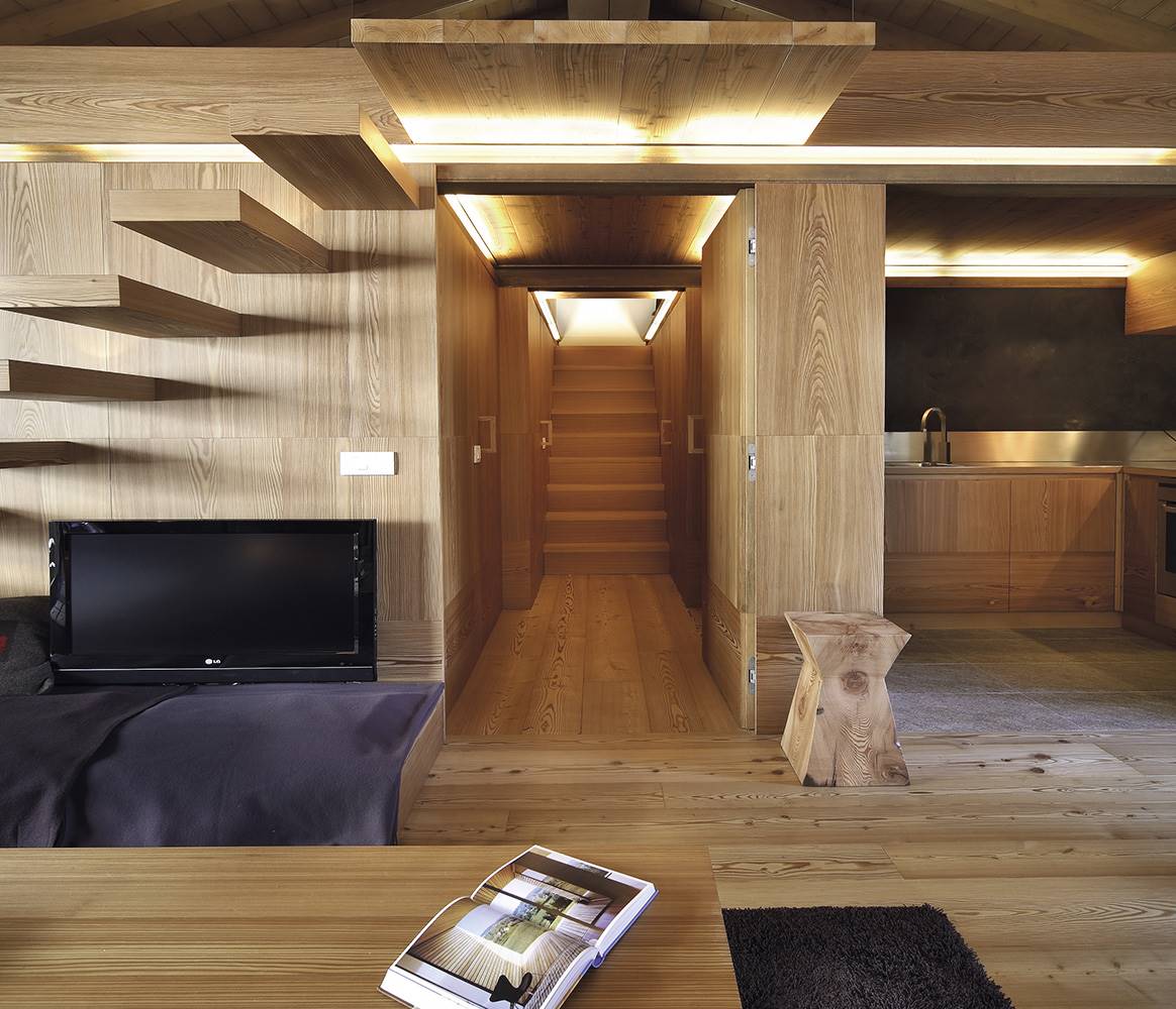 En este espacio diseñado por Studio Fanetti, la iluminación prescinde de lámparas a la vista ya que se ha preferido que queden ocultas en la propia arquitectura, retroiluminando la madera.
