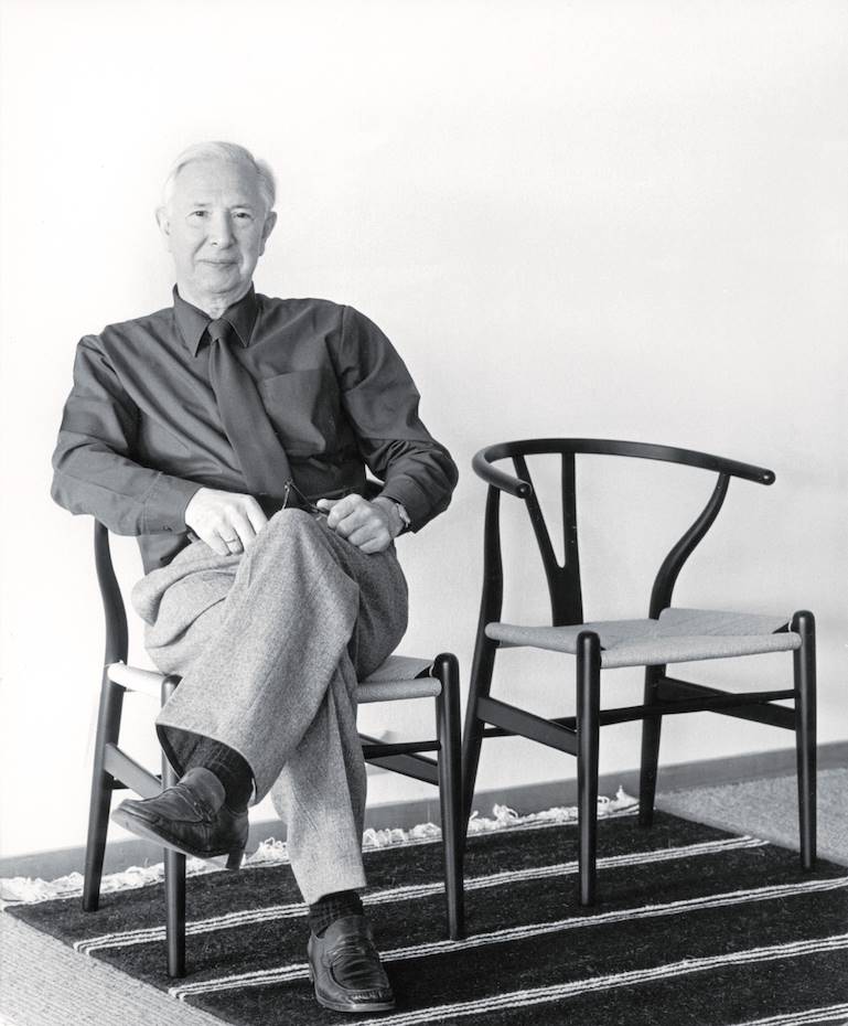 Hans J. Wegner sentado en una de las sillas CH24 que produce Carl Hansen & Søn
