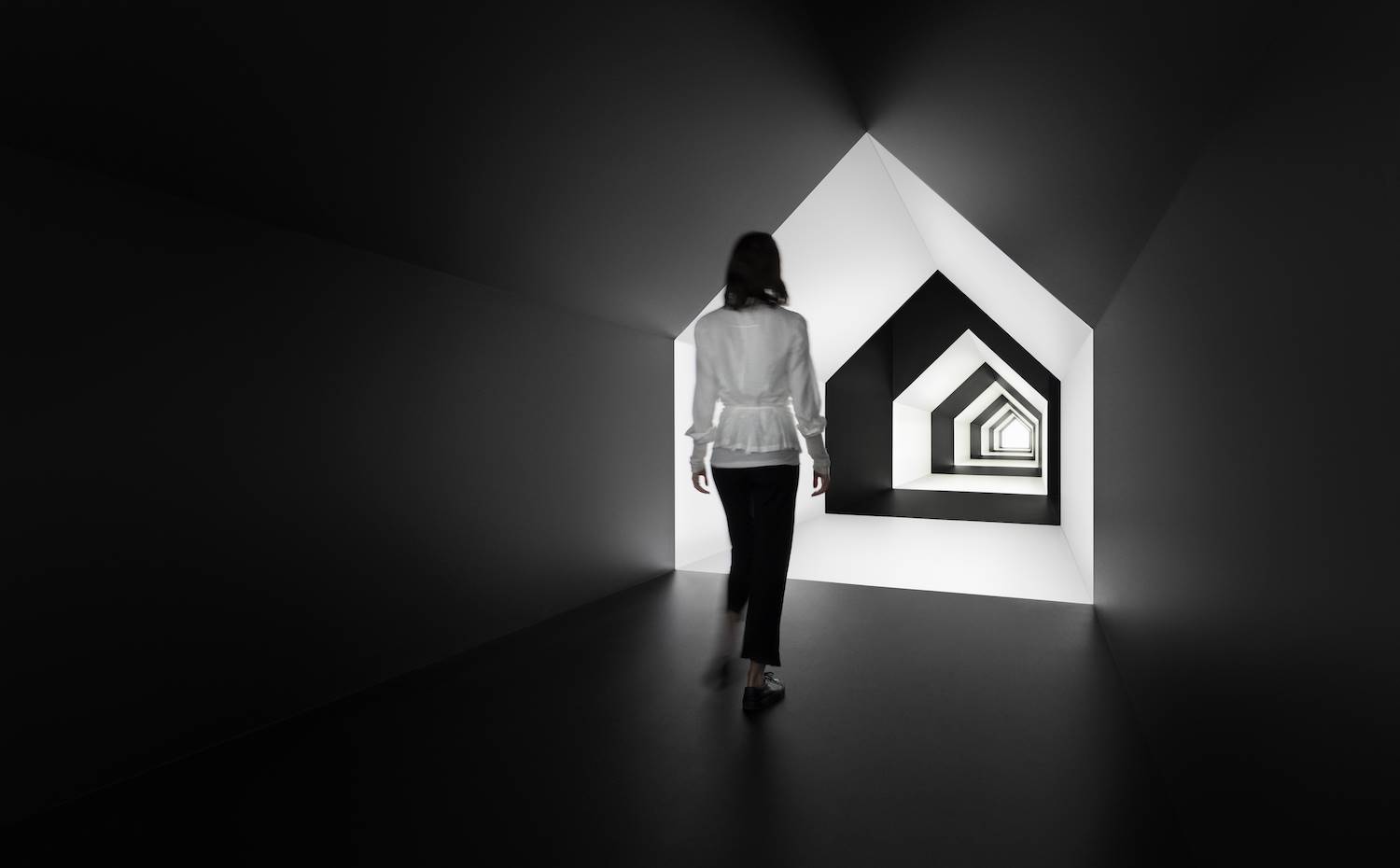 Un pasillo en forma de casa juega con la sensación espacial gracias a la combinación de blanco y negro