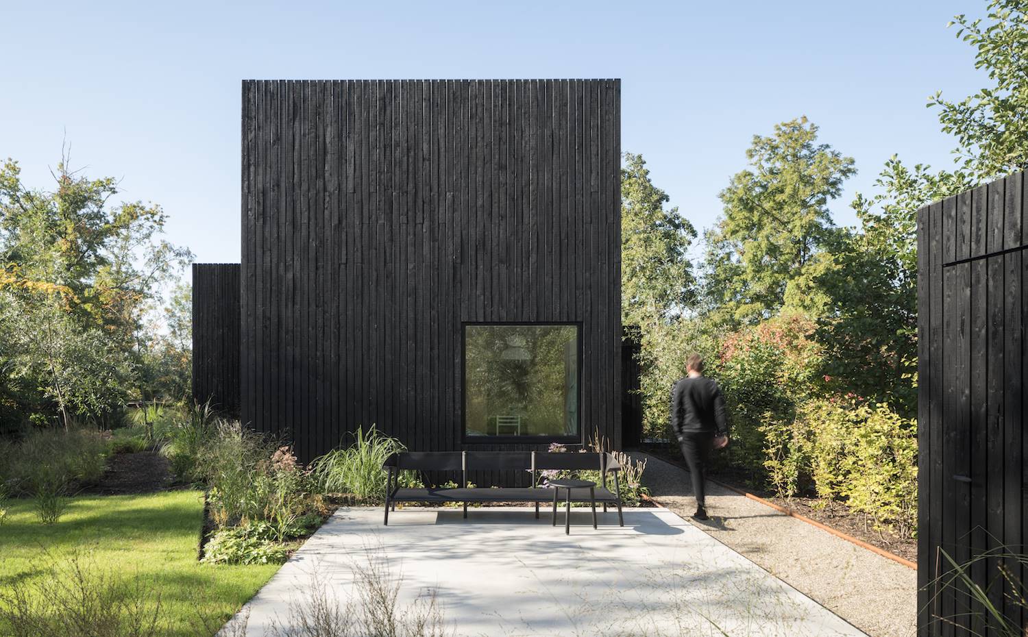 El exterior aparece como un volumen casi escultórico de listones de madera de pino teñidos de negro.