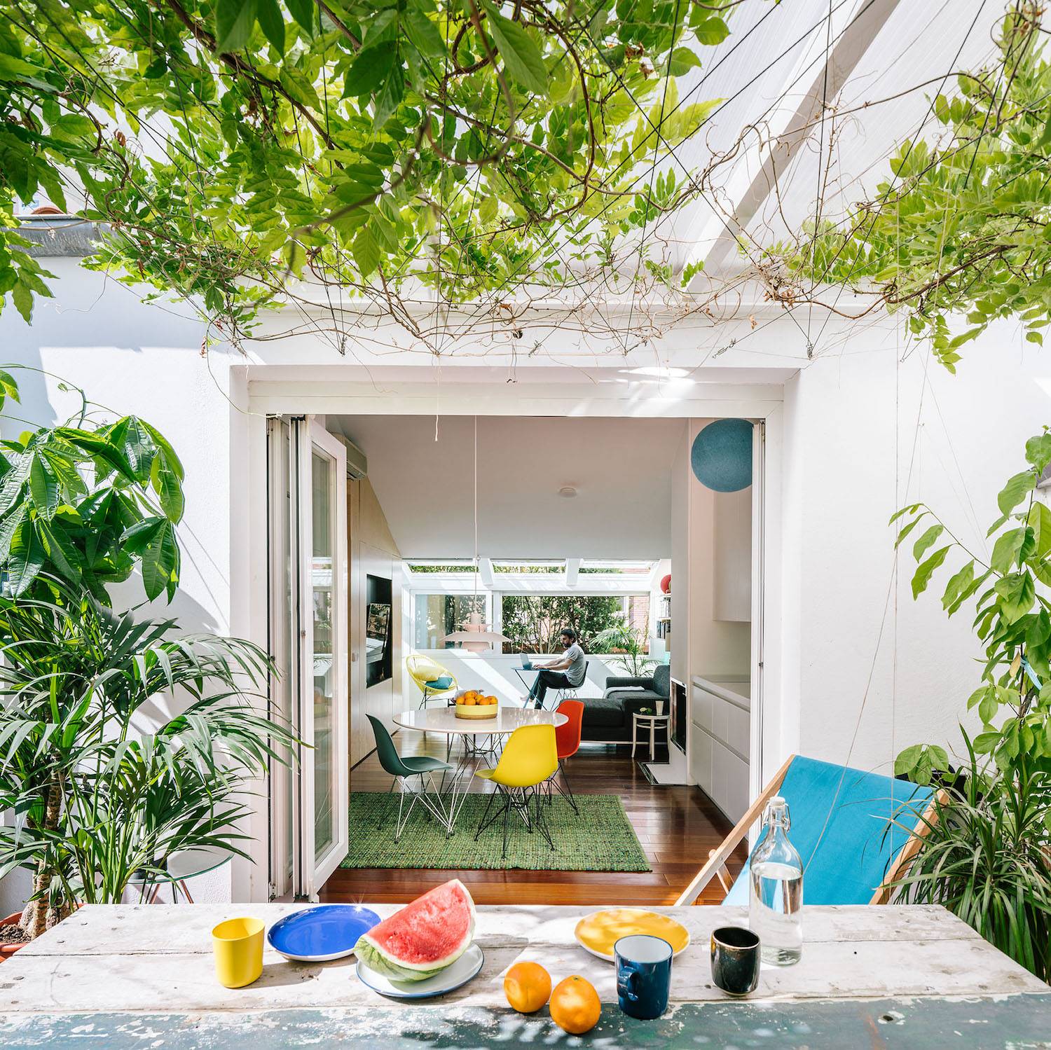 La cocina y el salón desde el exterior. La cocina y el salón vistos desde el exterior. Se ha escogido un mobiliario colorido como la silla Acapulco o las Plastic Chairs.