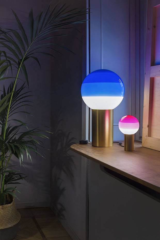 La lámpara Dipping de Jordi Canudas para Marset está disponible en varios tamaños. Su diseño se trata de pantalla de cristal con un degradado de colores y una base cilíndrica de l