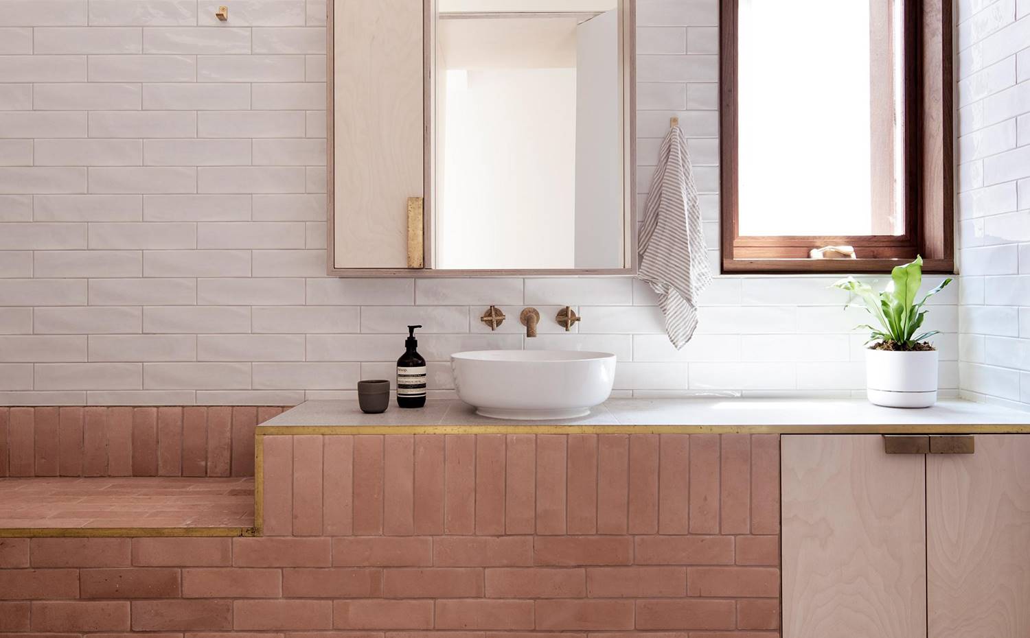 Baño revestido de cerámica, lavamanos exento, asiento de obra, grifería empotrada. Posiblemente una de las estancias más sofisticadas de la vivienda, equipada con lavamanos exento y grifería empotrada en acabado bronce, todo ello acompañado de revestimiento cerámico.