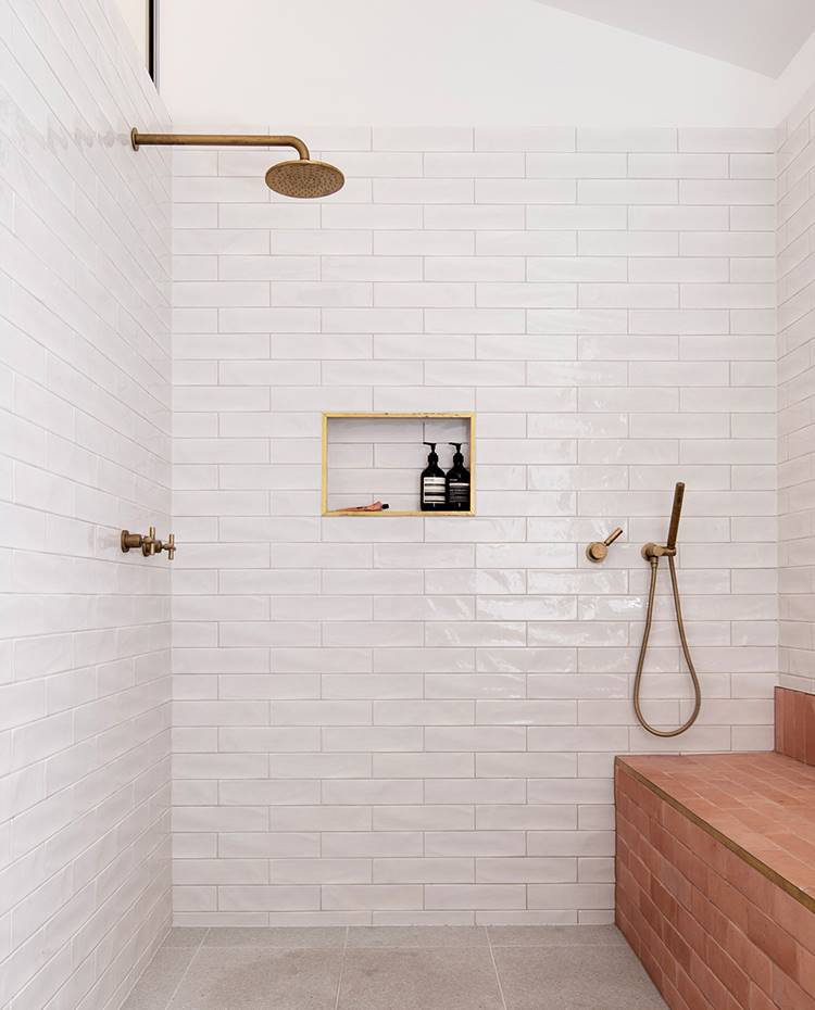 Ducha cuarto de baño, grifería empotrada, estante de obra para jabones, revestimiento de baldosas. La amplia ducha de obra a ras de suelo se acompaña de una hornacina empotrada con marco de bronce y con un banco de azulejos.