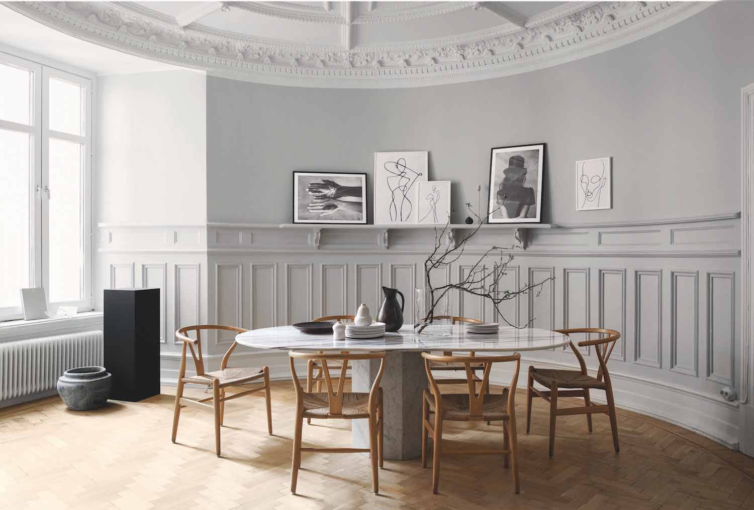 Comedor de SundlingKickén blanco con friso de madera mesa de mármol y sillas de CH24 de Carl Hansen
