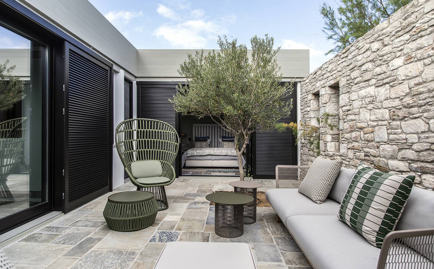 casa kettal grecia 01 terraza mobiliario exterior piedra. Butaca Cala, de Doshi Levien. El sofá y las mesas auxiliares son de la colección Mesh, de Patricia Urquiola. Puf Zigzag, de Emiliana Design Studio. Todo es de Kettal