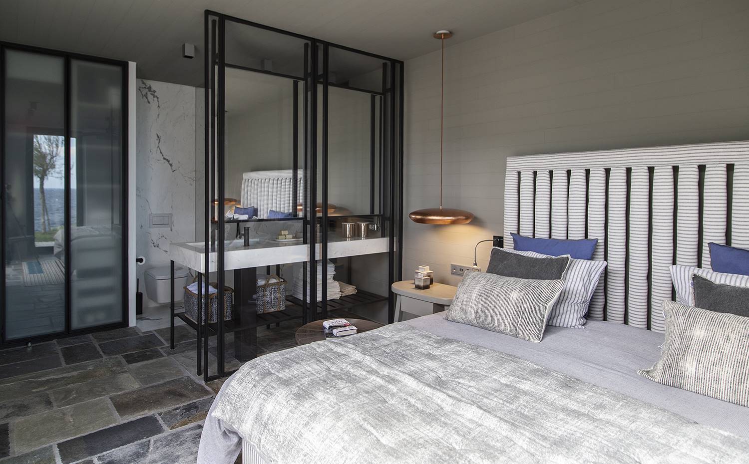casa kettal grecia 07 dormitorio baño integrado. Cama diseñada por Katerina Veremi Xynogala, al igual que la estructura metálica que separa el dormitorio del baño. Ropa de cama y cojines, de Scapa Home. Lámpara de suspensión, de Hind Rabii