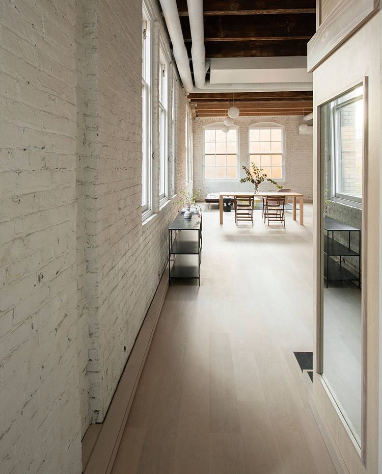Zona de paso, loft industrial, pared de obra vista, conductos de ventilación sobre listones de madera. Zona de paso desde la entrada al comedor y salón. Para el mobiliario, se ha optado por piezas de baja altura para permitir una mayor entrada de luz natural desde las ventanas arqueadas.  