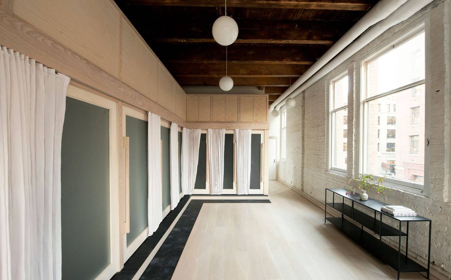 Sucesión de puertas de cristal esmerilado, cortinas blancas, grandes ventanales, vivienta tipo loft. El lavabo, la ducha, el inodoro y la sauna se integran (por separado) en una caja de madera blanca en forma de L que se acomoda perfectamente en una esquina de la vivienda. 