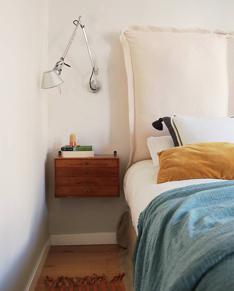 Dormitorio, lámpara auxiliar aplique, mesilla suspendida, cabecero cama tapizado. Detalle del dormitorio principal con mesilla suspendida y aplique Tolomeo, de Artemide. La fuerte presencia de telas en la decoración de la estancia favorece la sensación de calidez.