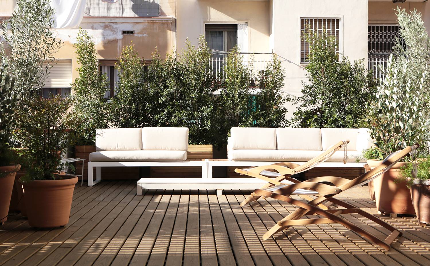 Terraza exterior vivienda, mobiliario exterior, tumbonas, vegetación. Junto con las celosías, la vegetación es una gran aliada en la gran terraza de este apartamento para preservar la privacidad frente a las viviendas vecinas.