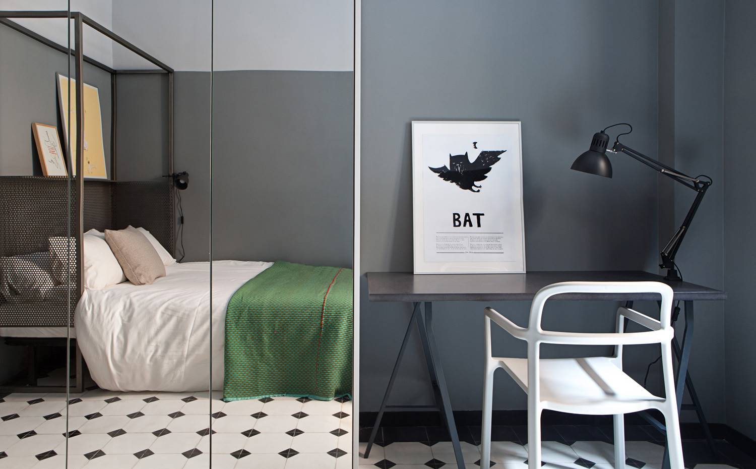 Dormitorio con ropa de cama verde, estanteria de acero en cabecero, reflejo armario de espejo, mesa y silla de zona de trabajo