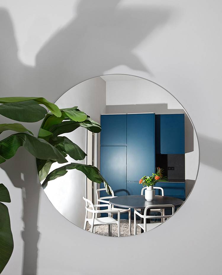 Reflejo cocina espejo, mueble almacenaje azul, mesa comdor negra, sillas blancas. El arte, el diseño y la arquitectura son fuente de inspiración para el estudio Plutarco, artífice del proyecto. Su propuesta, lejos de convencionalismos, aporta una marcada personalidad al espacio.