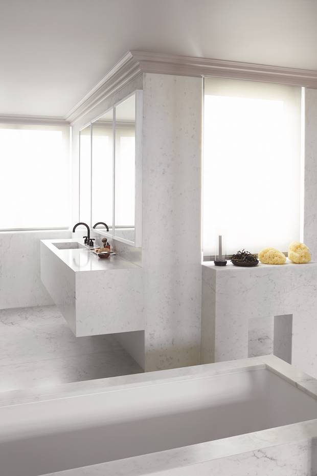 Baño con muebles hechos a medida en marmol blanco de un apartamento en Paris. El mármol de Carrara, omnipresente en las superficies del baño al igual que en el resto del apartamento, ha sido cuidadosamente elegido por su grano poético. Su presencia crea un lujo “radical” porque se ha prescindido de toda ornamentación y de cualquier elemento superfluo.