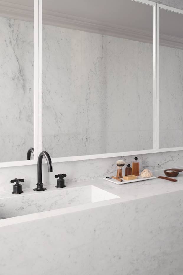 Baño con paredes de marmol y griferias negras de un apartamento en Paris. Aunque la espaciosidad no es un problema en este apartamento, la unidad tonal y matérica no solo crea la ilusión de mayor amplitud, sino que también permite añadir profundidad, textura y armonía a cada uno de los ambientes.