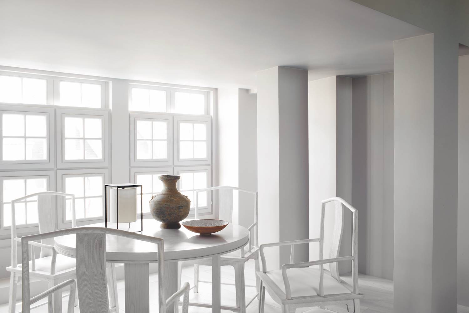 En el comedor, las líneas marcadas, las impecables proporciones y la paleta monocroma del espacio se equilibran con la suavidad que aportan las formas curvas del mobiliario y las texturas de los detalles decorativos.