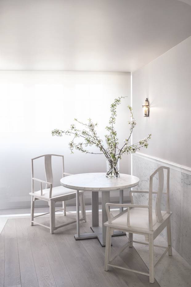 Rincon con una mesa redonda de marmol y sillas blancas de un apartamento en Paris. En la cocina, los sillones Tao, de Gillaume Alan, y la mesa redonda están perfectamente relacionados con la arquitectura, todo en madera de fresno y mármol. El mismo mármol se usa en el friso de la pared y en el marco que delimita y contrasta con la tarima de madera de roble.