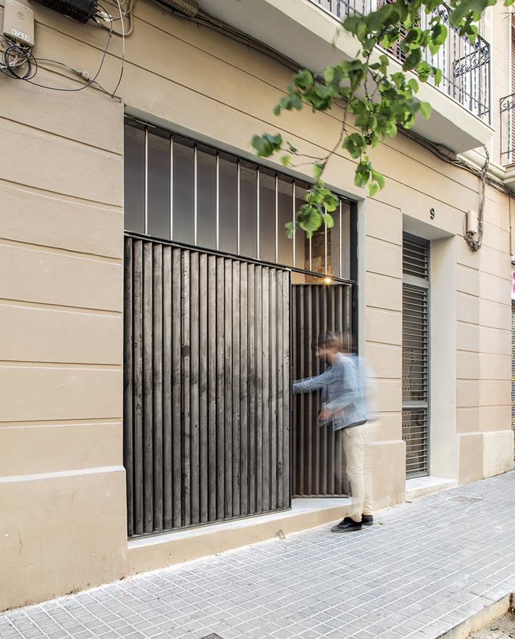 Acceso exterior desde calle, puerta de hierro. Al interior de la vivienda se accede desde la propia calle a través de un cerramiento de hierro y cristal que deja que la luz natural penetre hasta el interior. 