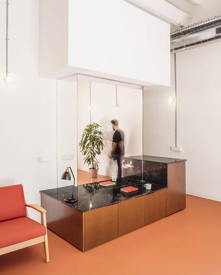 Mueble salón de madera y encimera de granito, sofá de madera y tapicería en rojo. El uso de espejos a lo largo de toda la vivienda, como se muestra en este frente, aporta mayor sensación de amplitud al conjunto
