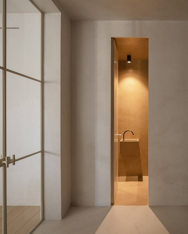Zona de paso con puerta cristal transparente, entrada baño, lavamanos suspendido. El cuarto de baño sigue las líneas depuradas y diseño minimalistas que impera en este proyecto, obra del estudio madrileño Beta.Ø.