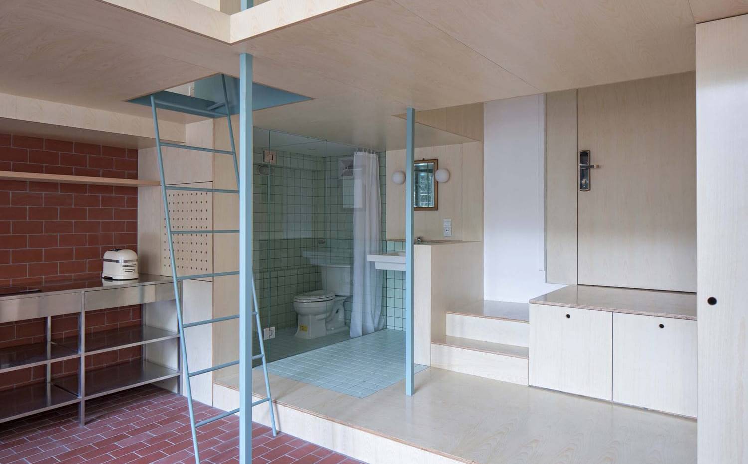 Zona de entrada elevada, baño aislado tras mampara. Junto a la puerta de acceso se habilita el baño semiabierto, delimitado con la elección de un revestimiento de diferente color.
