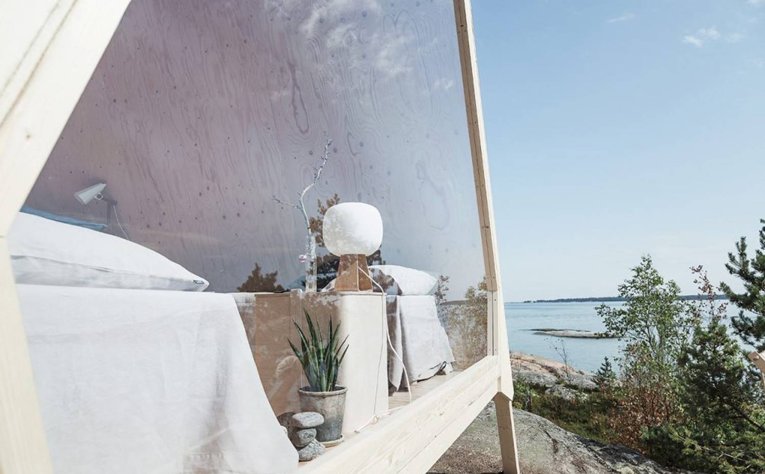 Detalle interior cabaña ecológica, lámparas y plantas junto a la ventana. Para que sea funcional y eficiente en términos de consumo energético, la cabaña debe ser lo más compacta posible.