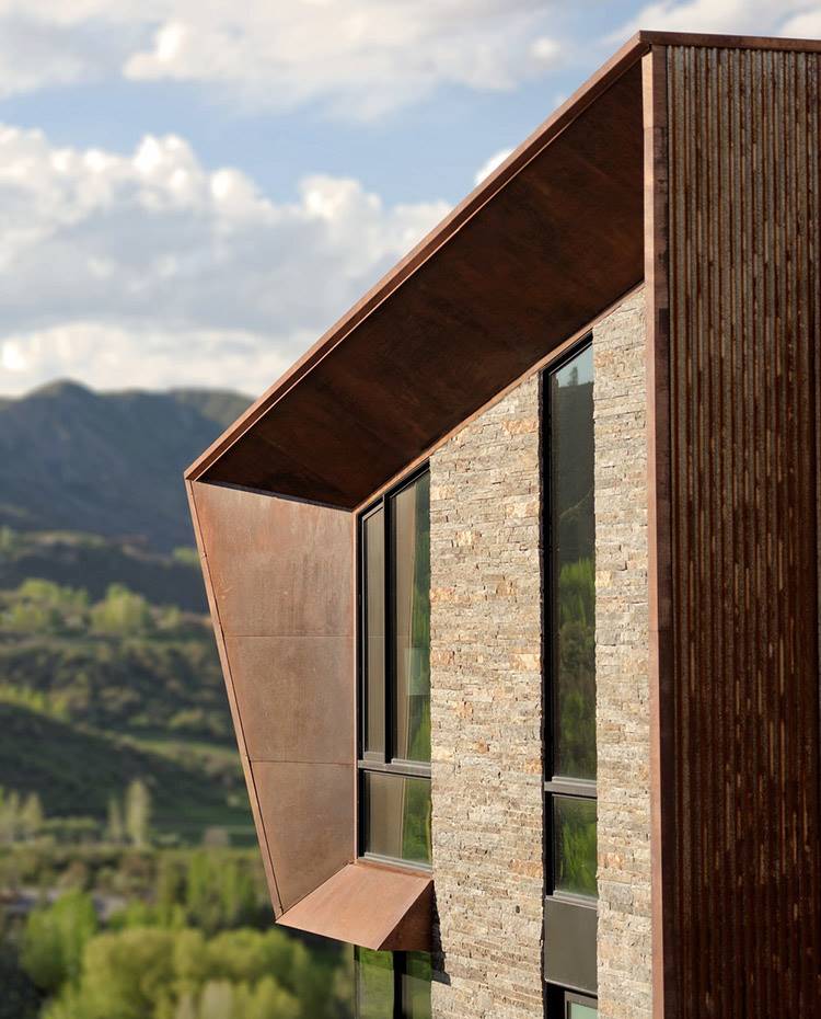 Detalle cerramiento exterior a base de acero corten con ventanas de crital y estrucutra de piedra. De acuerdo con las estrictas restricciones ambientales de la zona en cuanto a altura y pendiente, la casa fue construida en otro sitio y luego anclada directamente en el enclave elegido. 