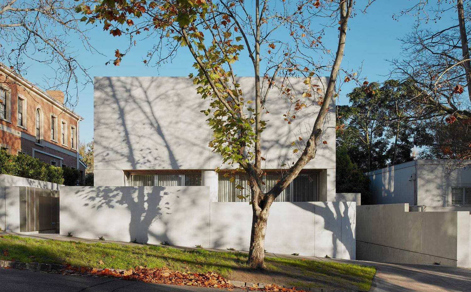 Exterior vivienda, zona residencial, fachada monolítica gris con murete escalonado gris. La sólida fachada monolítica de la vivienda proporciona la privacidad visual y acústica que buscaban sus propietarios. 