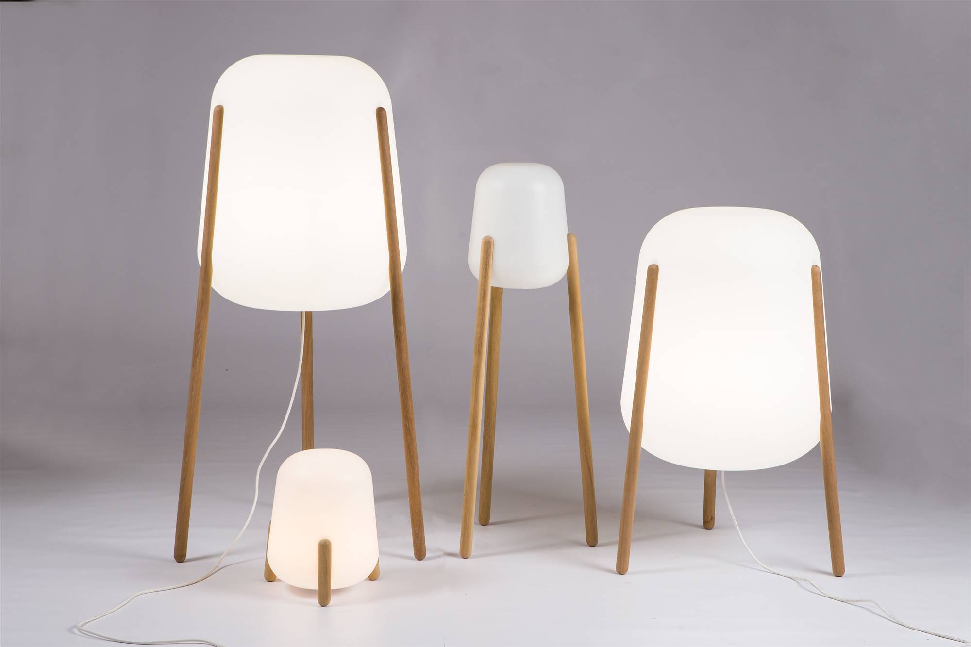 Lámpara de exterior Llum fabricada en polietileno, que ilumina en todas direcciones, y se mantiene suspendida sobre tres pies de madera torneada. Diseñada por CrousColagero