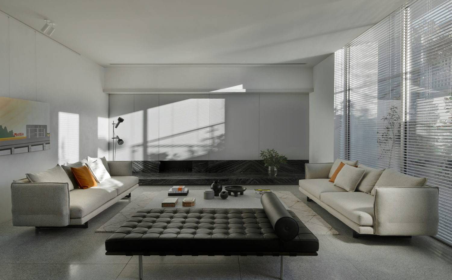 Salón con dos sofás enfrentados, chaise-longue negra, zona delimitada con alfombra, frente mobiliario gris con chimenea. En el interior de la vivienda proyectada por el estudio Davidov Architects, se hace evidente el trazado a base de líneas limpias y visión en profundidad.