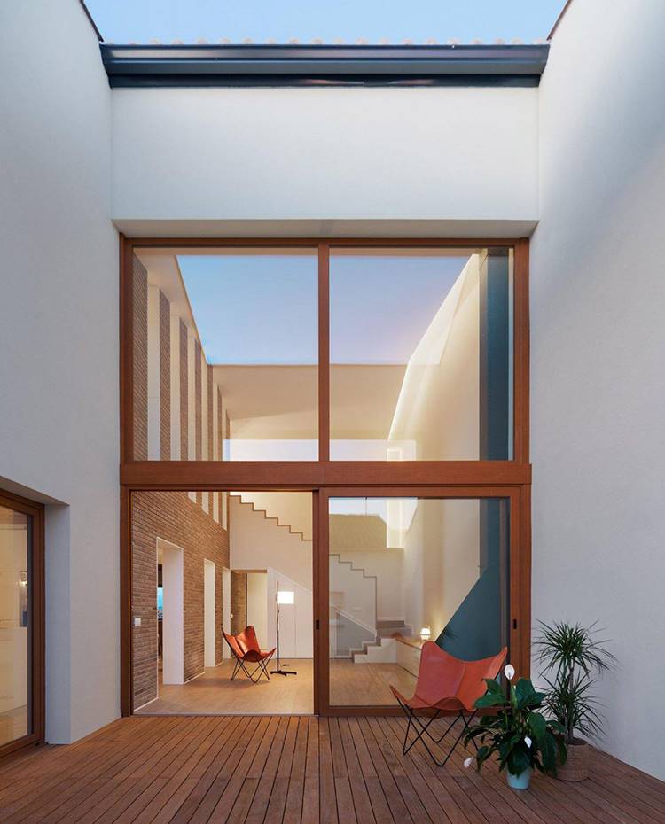 Terraza exterior con suelo en listones de madera, cerramiento a cristalado a gran altura. El proyecto llevado a cabo por Hiha Studio se ha basado en actualizar y adaptar el edificio existente a los nuevos tiempos, nuevos materiales y a las nuevas maneras de vivir.