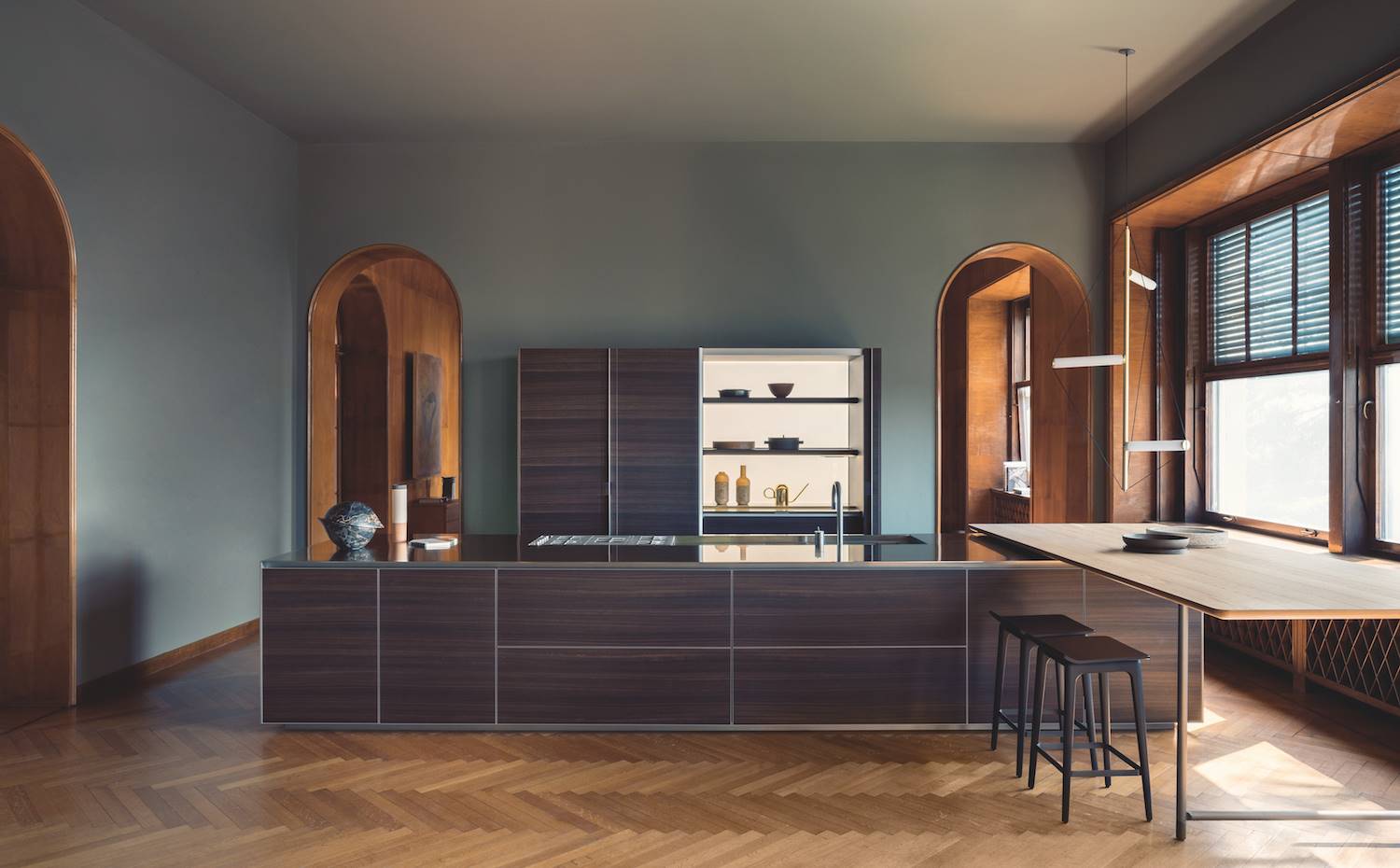 Cocina en sila con mesa auxiliar y pared con arcos pintada de color azul
