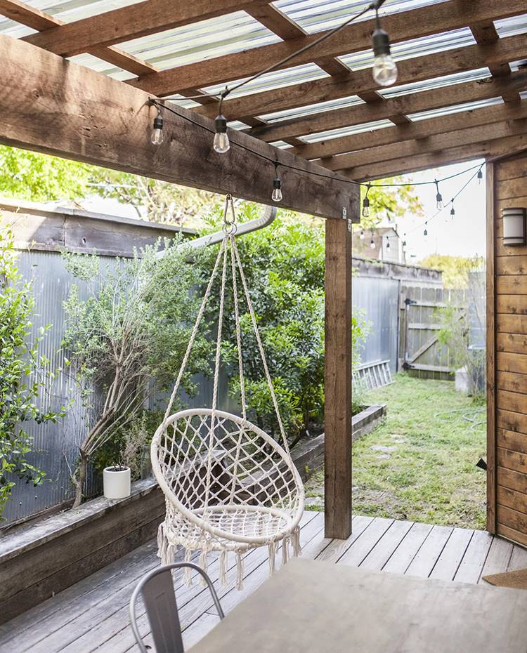 Jardín trasero de la casa, silla colgada de estructura madera, cobertizo, silla industrial. El jardín, equipado con un agradable porche cubierto, está rodeado de hierbas aromáticas y plantas favorables a los polinizadores con el fin de atraer abejas y mariposas.