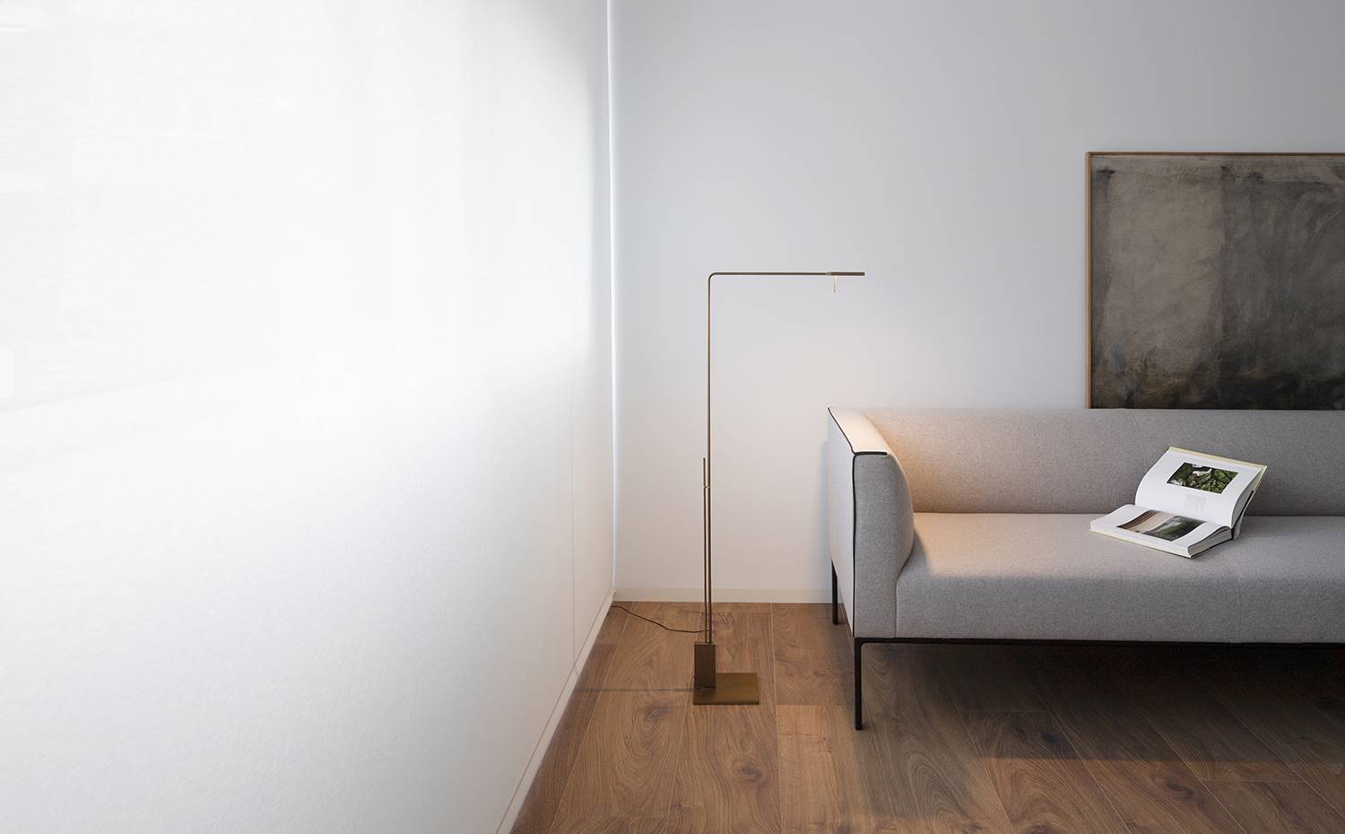Salón, lámpara de pie junto a sofá gris, suelo de madera. La austera decoración, a base de piezas de líneas muy puras y tonos neutros, realza aún más la percepción del apartamento como una continua forma escultórica.
